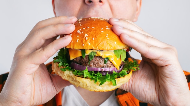 Un chico joven está sosteniendo una hamburguesa fresca.