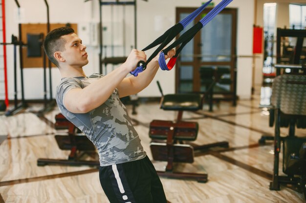Un chico joven y fuerte en los trenes de ropa deportiva en un gimnasio