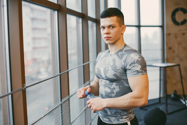 Un chico joven y fuerte en los trenes de ropa deportiva en un gimnasio