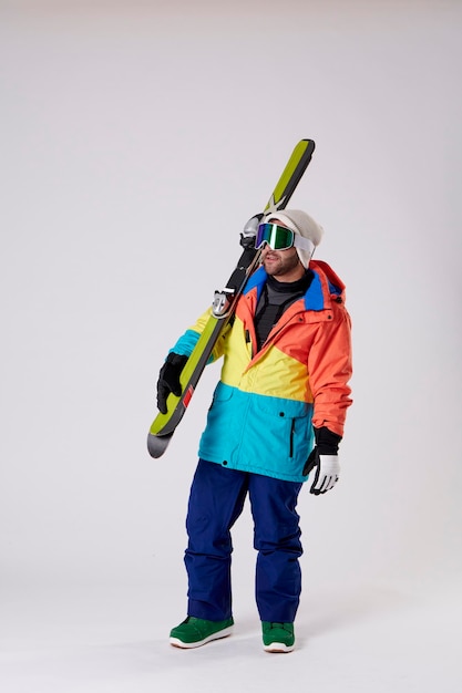 Foto chico joven con gafas de snowboard sosteniendo unos esquís