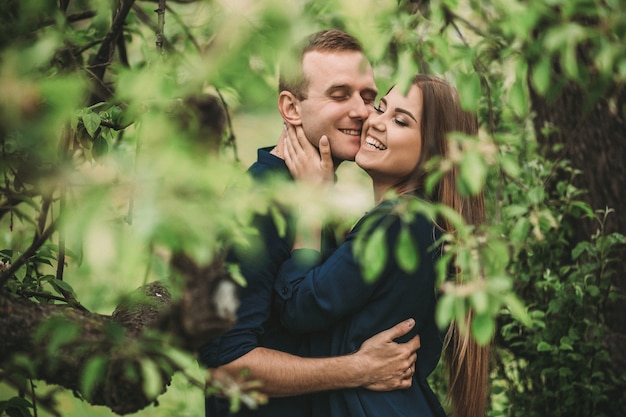 Chico joven guapo con una chica de pie en el jardín de primavera. Pareja romántica está caminando en el parque. Concepto de relación feliz