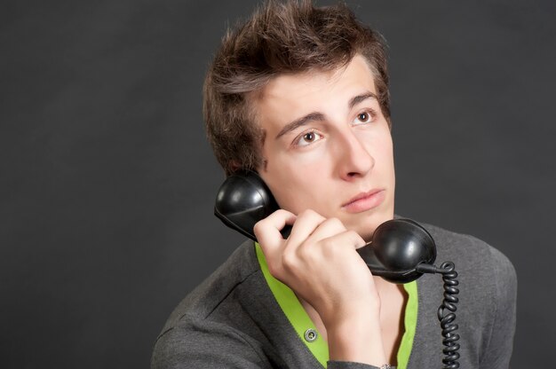 Chico joven hablando por el viejo teléfono