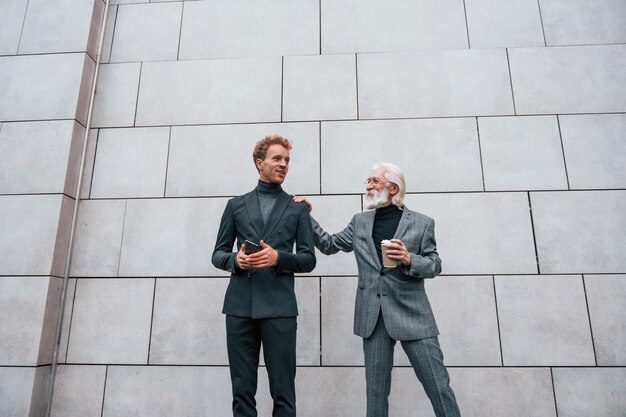 Chico joven con hombre mayor en ropa elegante está al aire libre juntos Concepción de negocios