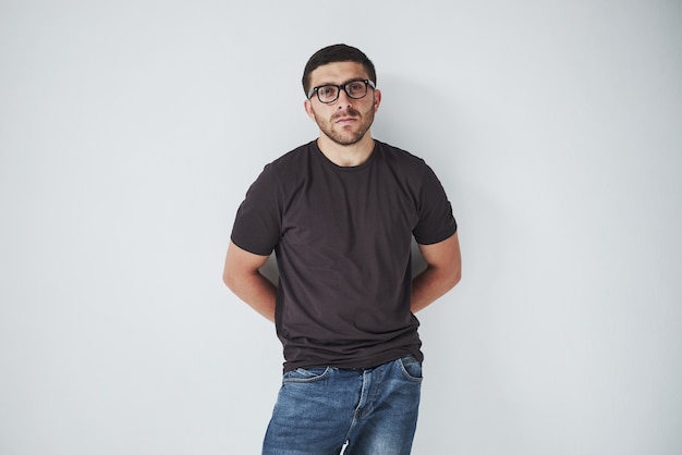 Chico joven inconformista con gafas riendo felizmente aislado sobre fondo blanco.