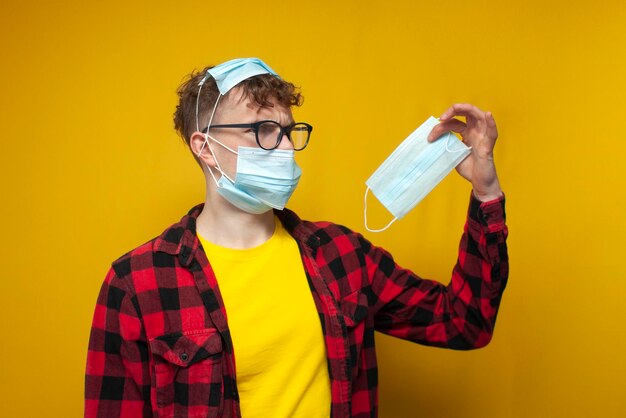 Chico joven con máscaras médicas cerradas muchas máscaras covid en la cara del chico y estrés pandémico en la cabeza