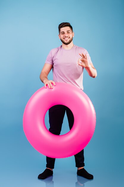 Chico joven del Medio Oriente con anillo de goma rosa para nadar en azul