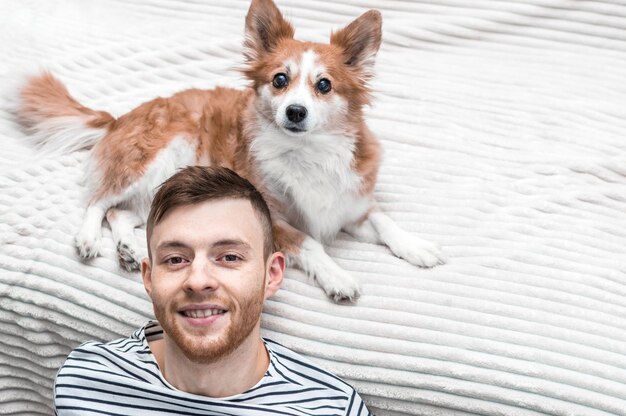 Chico joven y perro. Retrato en la cama del apartamento.