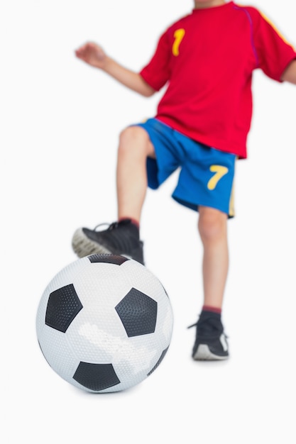 Foto chico joven con pie en balón de fútbol