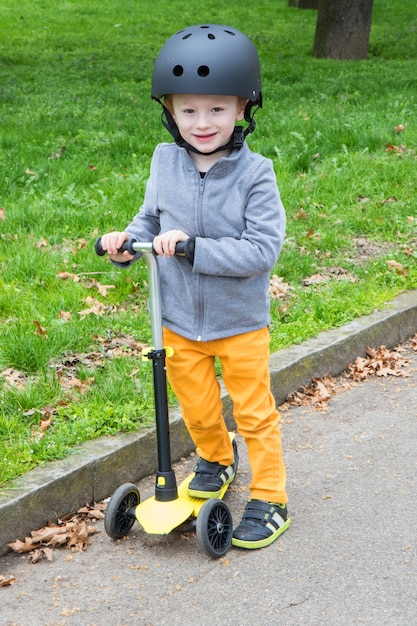 Chico joven con scooter amarillo en el parque