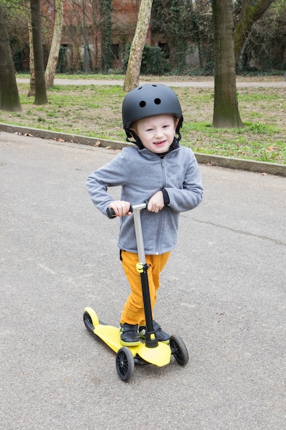 Chico joven con scooter amarillo en el parque