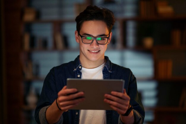 Foto chico joven sonriente sosteniendo usando tablet pc digital en la oficina