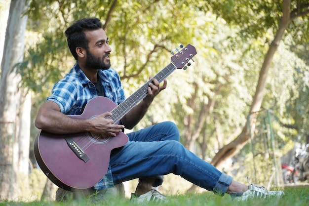 Chico joven con su guitarra y tocando la guitarra