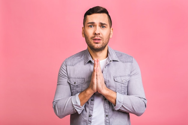 Chico joven vestido de manera informal, juntando las manos en oración o meditación