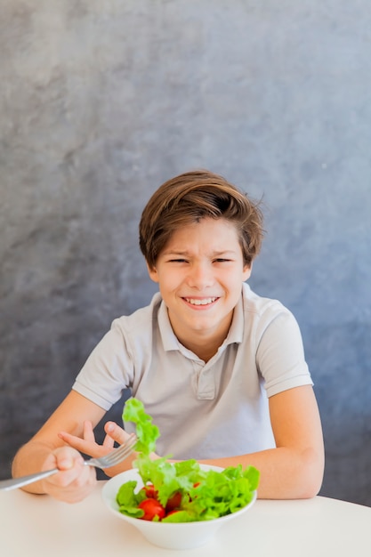 Foto chico lindo adolescente comiendo ensalada