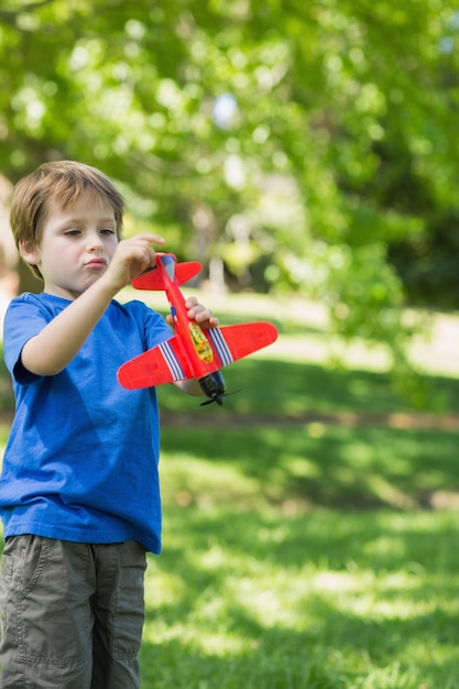 Chico lindo con avión de juguete en el parque