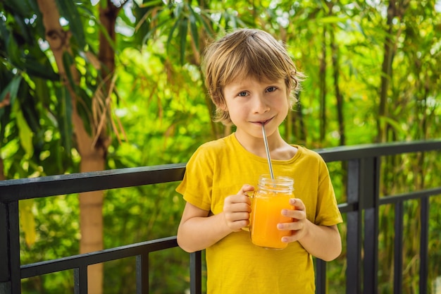 Chico lindo bebiendo jugo de naranja para el desayuno