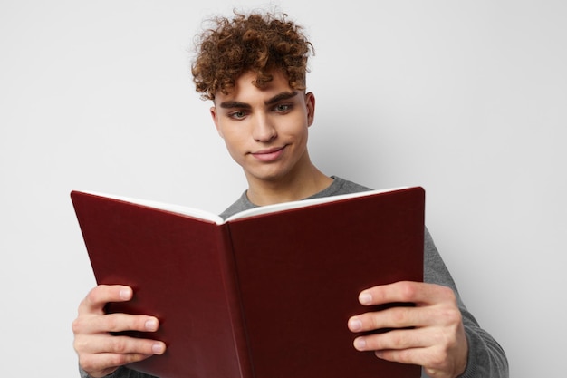 Chico lindo con cabello rizado con un libro en sus manos entrenando