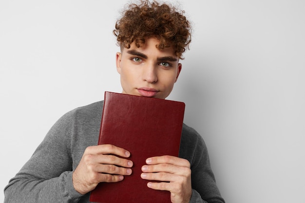 Chico lindo con cabello rizado con un libro en sus manos entrenando