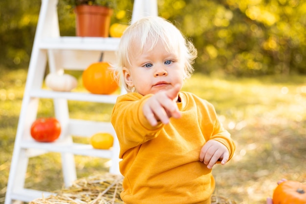 Chico lindo con calabazas en el fondo del parque otoño