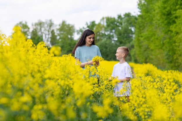 Un chico lindo con una camiseta blanca le da flores amarillas a su madre