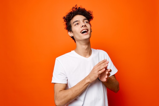 Chico lindo con camiseta blanca de pelo rizado vista recortada fondo naranja