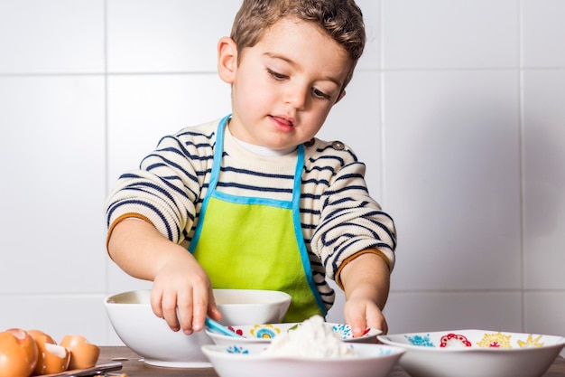 Un chico lindo con comida en la mesa.