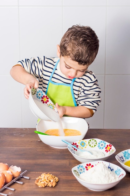Un chico lindo con comida en la mesa.