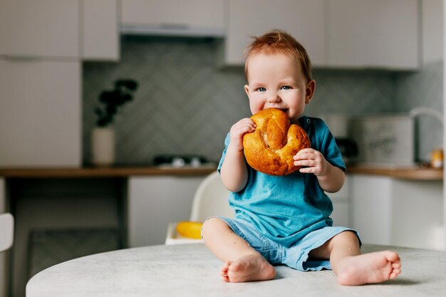 Un chico lindo comiendo pan en casa.