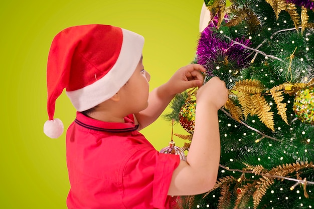 Foto chico lindo decorando un árbol de navidad
