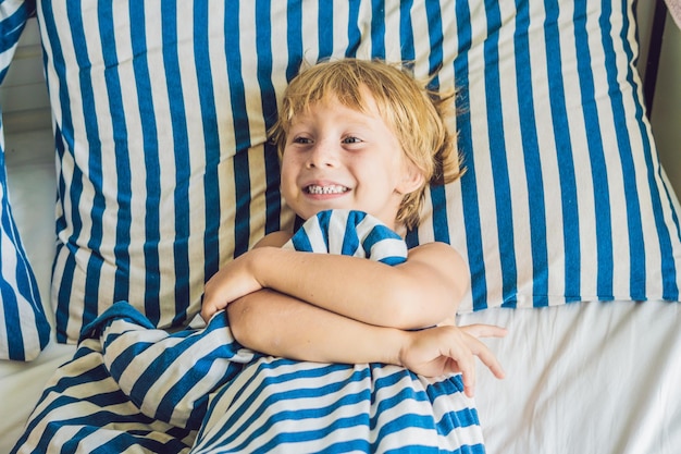 El chico lindo se despertó en su cama. Los niños duermen concepto