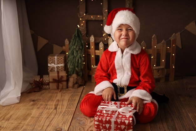 chico lindo disfrazado de santa tiene un regalo de año nuevo