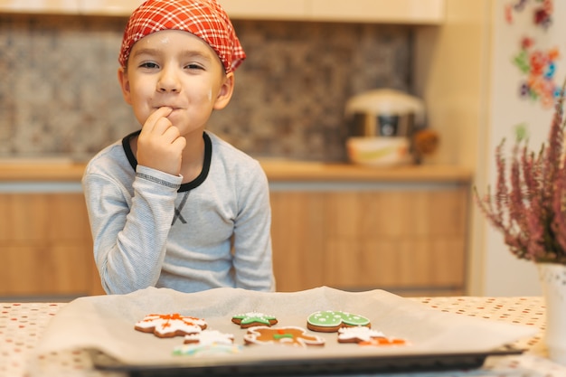 Chico lindo disfrutando el sabor de las galletas de Navidad con respaldo fresco.