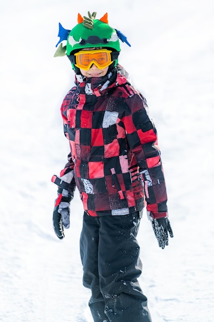 Chico lindo divirtiéndose haciendo snowboard en las montañas