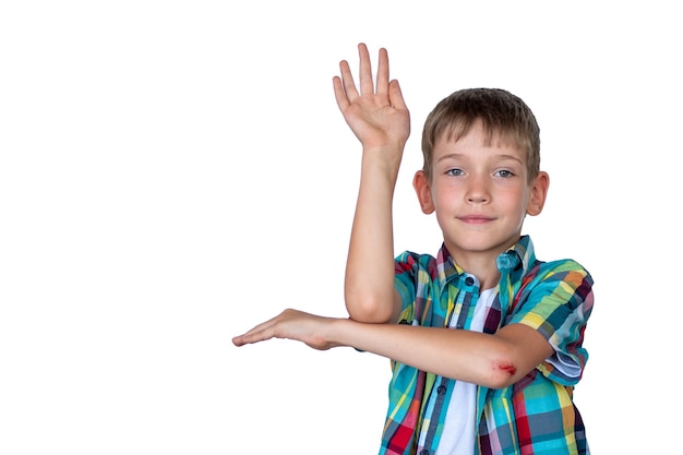 Un chico lindo e inteligente levanta la mano para responder en clase. Niño feliz contra una pizarra. Concepto de educación, concepto de regreso a la escuela