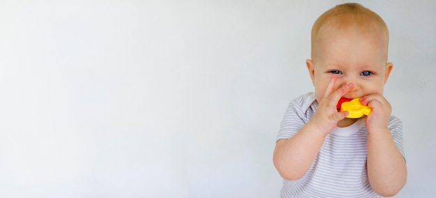 Un chico lindo está masticando un juguete sobre un fondo blanco Dentición en niños