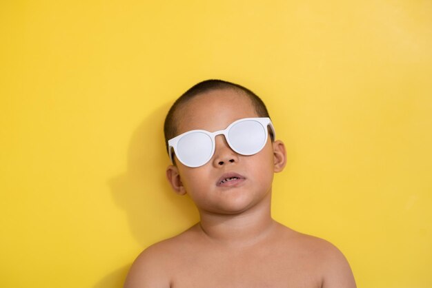 Chico lindo en gafas de sol sobre fondo amarillo mirando con una sonrisa Descuento Venta Vacaciones de verano