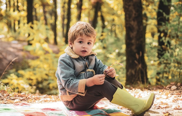 Chico lindo con hojas de otoño sobre fondo de naturaleza de otoño