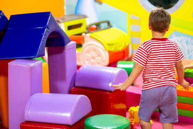 Chico lindo jugando con bloques de colores de juguete de construcción Actividades preescolares y primera infancia