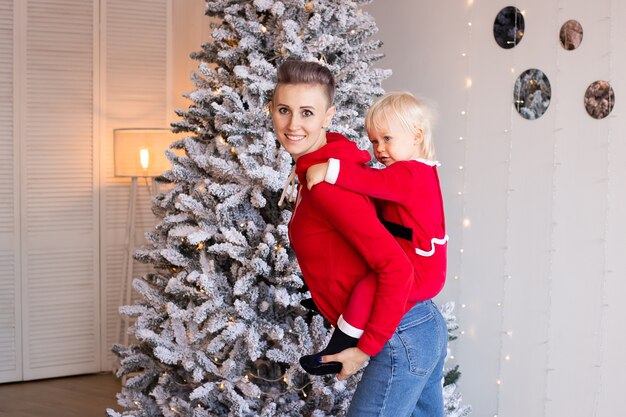 Chico lindo y madre cerca del árbol de Navidad. Concepto de Navidad, vacaciones e infancia.