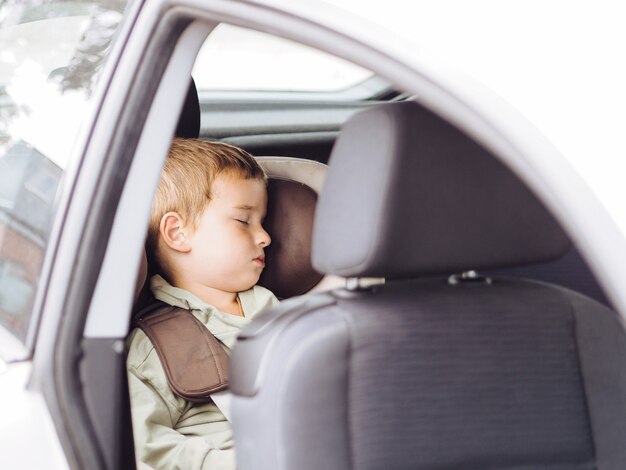 Chico lindo niño durmiendo en un coche en el asiento de seguridad