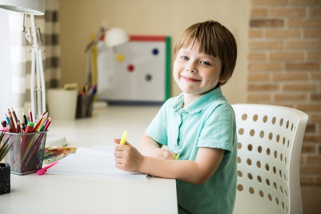 Chico lindo niño haciendo los deberes. Dibujo de niño inteligente en el escritorio. Colegial. Dibujo de estudiante de escuela primaria en el lugar de trabajo. Los niños disfrutan aprendiendo. Educación en casa. De vuelta a la escuela