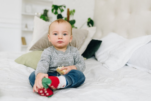 Chico lindo niño sentado en la cama con merienda