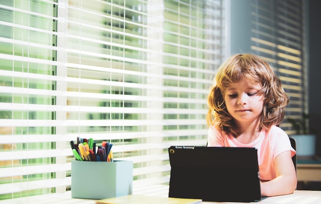 Chico lindo niño usando tableta en el escritorio en casa concepto de educación en línea conocimiento de educación para niños