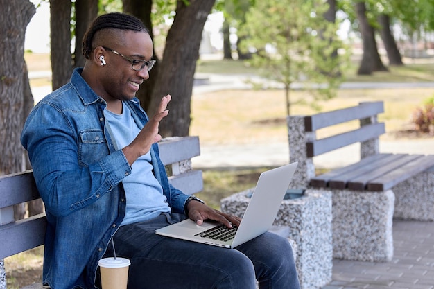 Chico lindo con peinado africano sentado en un banco le pregunta a un amigo en las redes sociales