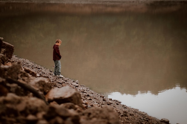 Foto un chico lindo de pie junto al lago