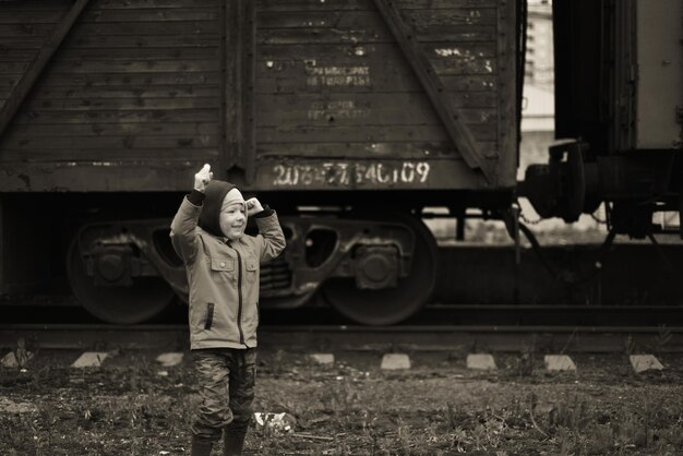 Foto un chico lindo de pie junto al tren durante el invierno