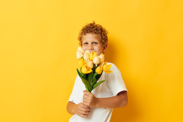 Chico lindo con un ramo de flores amarillas fondo aislado inalterado