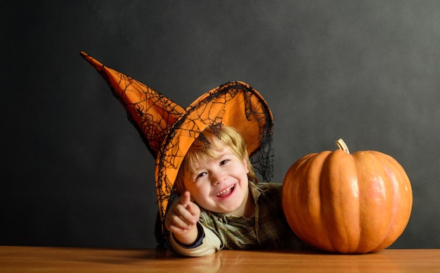 Chico lindo con sombrero de bruja con calabaza de halloween apuntándote niño truco o trato chico de fiesta de halloween