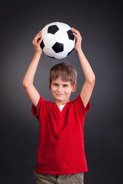 Foto chico lindo sosteniendo una pelota de fútbol