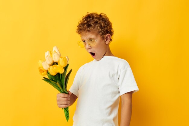 Chico lindo sosteniendo un ramo de flores un fondo aislado de regalo inalterado